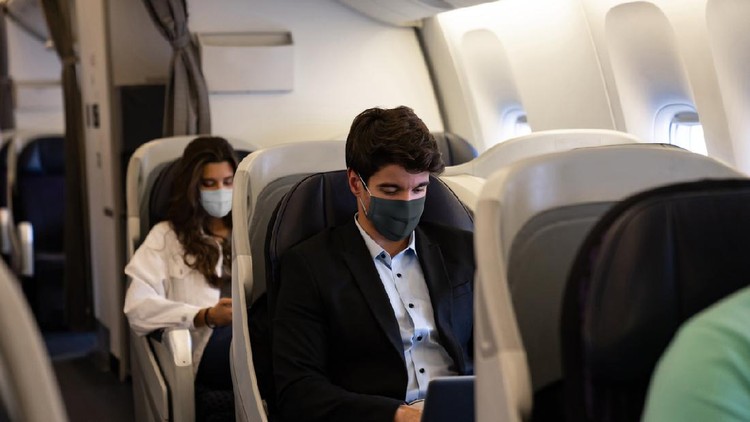Business man traveling and wearing a facemask on the plane while using his laptopâ COVID-19 pandemic lifestyle concepts