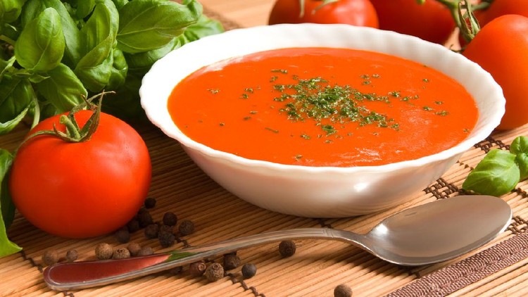 Tomato soup in a bowl with healthy and fresh ingredients and herbs
