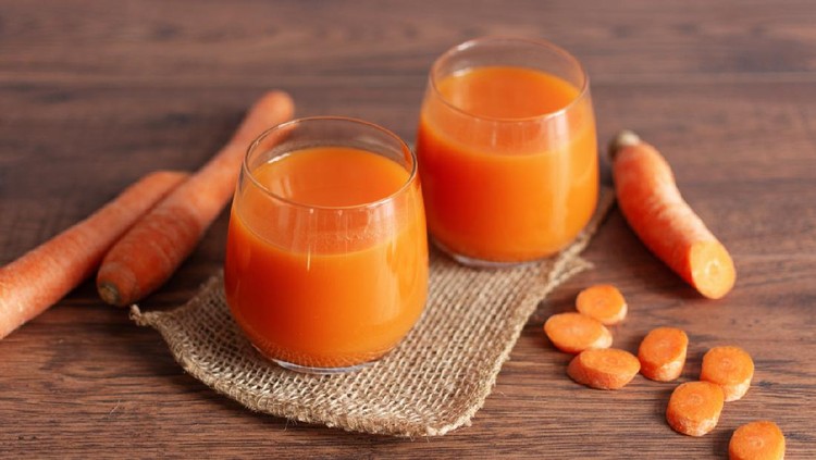 Healthy carrot juice in a glass and fresh carrots on a table. Healthy dieting drink in a glass on wooden table background.