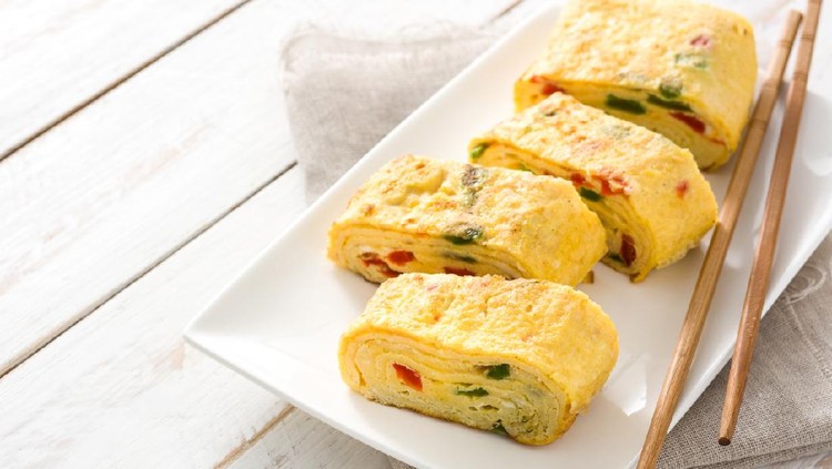 Traditional tamagoyaki Japanese omelette on white wooden table.