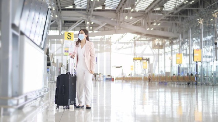 Ilustrasi wanita menggunakan masker di bandara