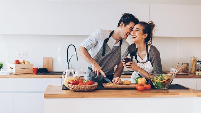 Affectionate couple preparing salad in a domestic kitchen