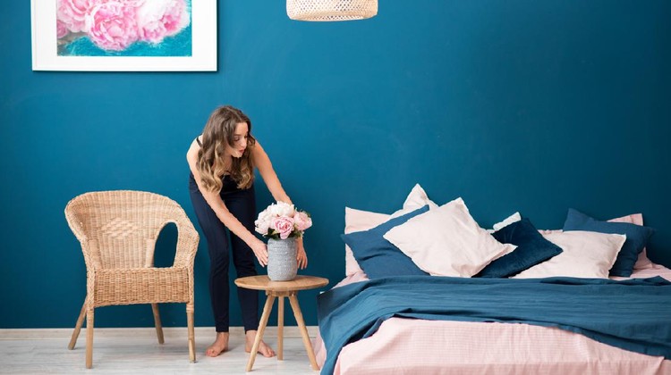 Young woman decorating bedroom with beautiful flowers at home