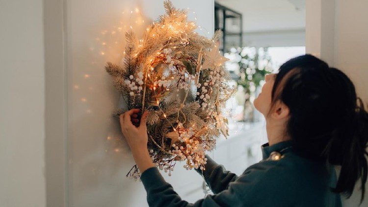 Photo of a young woman decorating the living room of her apartment; getting ready for the upcoming holiday season.