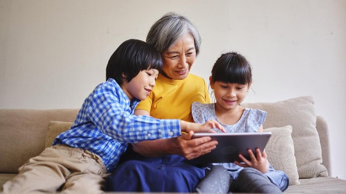 A Taiwanese grandmother reads from an electronic tablet to her grandchildren in a home in Taipei.