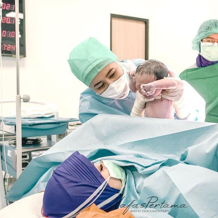 <p>Nathalie begitu bahagia ketika sang dokter memperlihatkan Si Kecil yang baru saja terlahir ke dunia. (Foto: Instagram @nathalieholscher / @nafaspertama)</p>