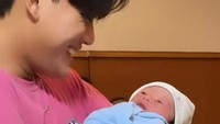 <p>Tak lama si sulung Rizky Febian akhirnya datang untuk melihat baby Adzam. Rizky tersenyum sambil menggendong adik kecilnya itu. (Foto: Instagram @nathalieholscher)</p>
