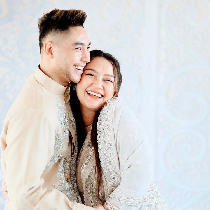 <p>Saat perayaan empat bulan kehamilannya, Siti dan Krisjiana tampak begitu bahagia. Keduanya tersenyum semringah mengenakan pakaian yang serasi. (Foto: Instagram @sitibadriahh)</p>