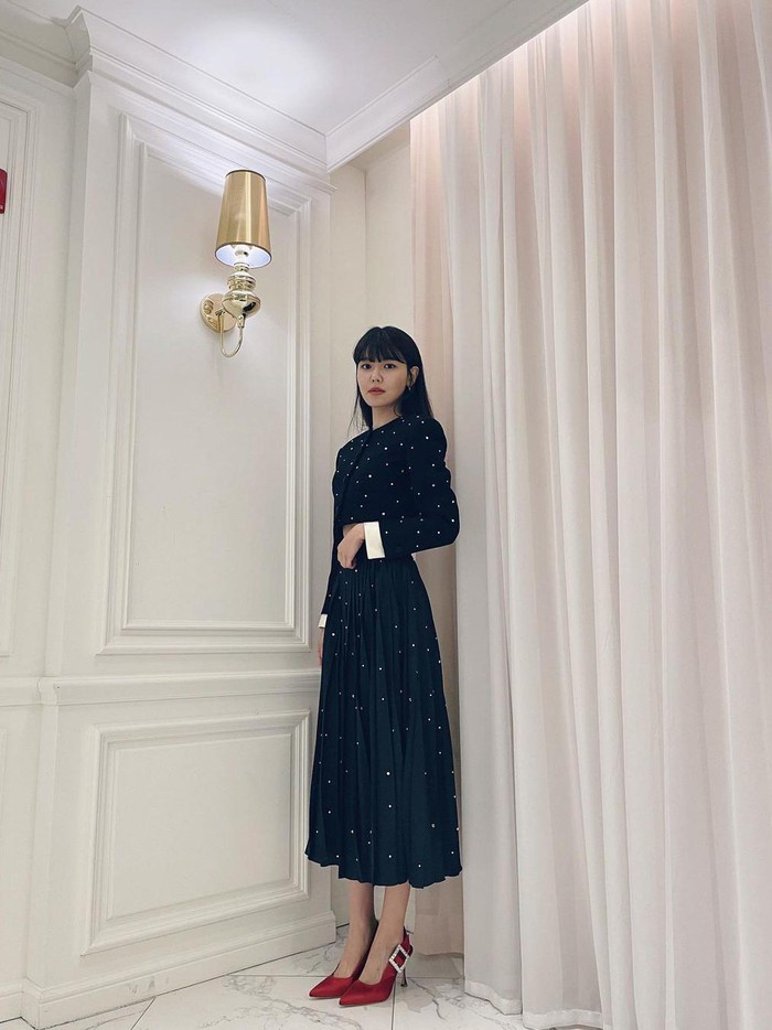 Tampil classy saat Natal dengan menggunakan warna hitam, yuk! Agar tampilanmu tidak biasa, coba pakai crop top dan padukan dengan rok plisket berwarna senada. Tambahkan heels merah sebagai dari tampilanmu./ Foto: Instagram.com/sooyoungchoi