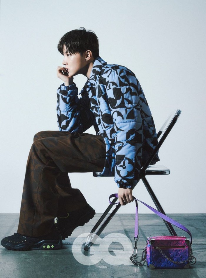 Dikenal paling fashionable, Jhope mengenakan padding jaket berwarna biru dengan logo khas LV. Ia padankan dengan celana berwarna coklat dan sneakers hitam. Sling bag gradasi pink dan ungu menjadi point penting dalam tampilannya. (@voguekorea)