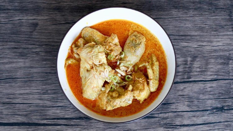 Indonesian gulai ayam or Indonesian chicken curry in a bowl on wood background.
