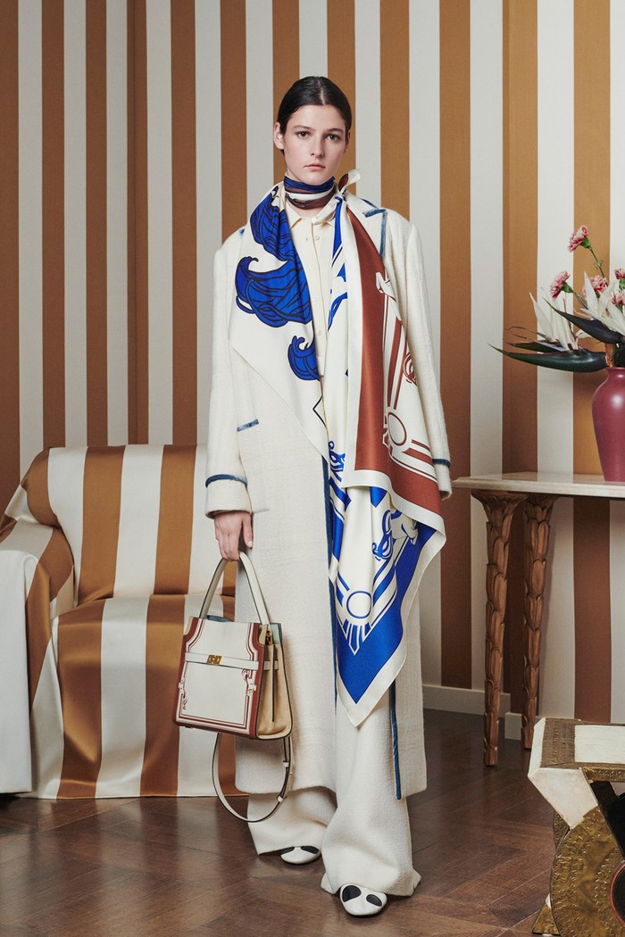 Corak scarf klasik dan feminin digubah ke dalam silut yang structured dan kontemporer. Kombinasi warna putih dengan biru dan coklat menampilkan kesan effortless.Foto: Courtesy of Tory Burch