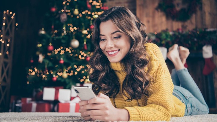 Low below angle view photo of charming, cute beautiful attractive girlfriend browsing through her phone in search of something while wearing jeans denim yellow sweater