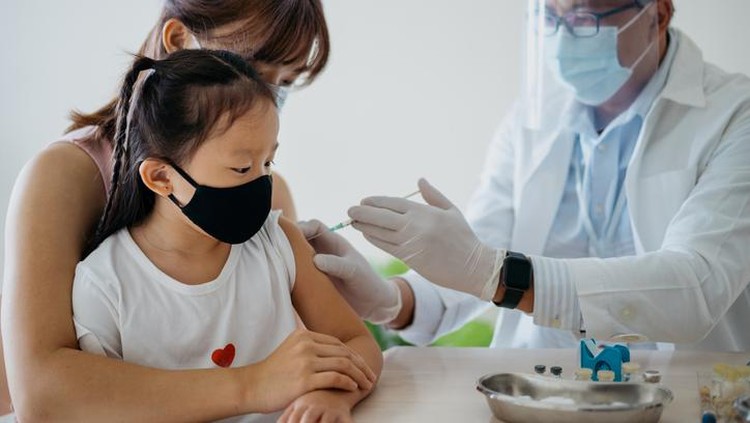 Vaksin Covid Anak 6-11 Tahun: Syarat-Cara Mengatasi KIPI Image of a young asian girl getting a vaccine injection on her arm from a healthcare worker. Woman accompanying her daughter to get a vaccine injection at medical clinic.