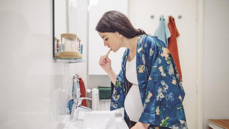 Ibu hamil sikat gigi At home - young woman brushing her teeth