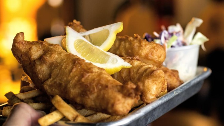 Holding a plate of Fish and Chips with coleslaw and fries