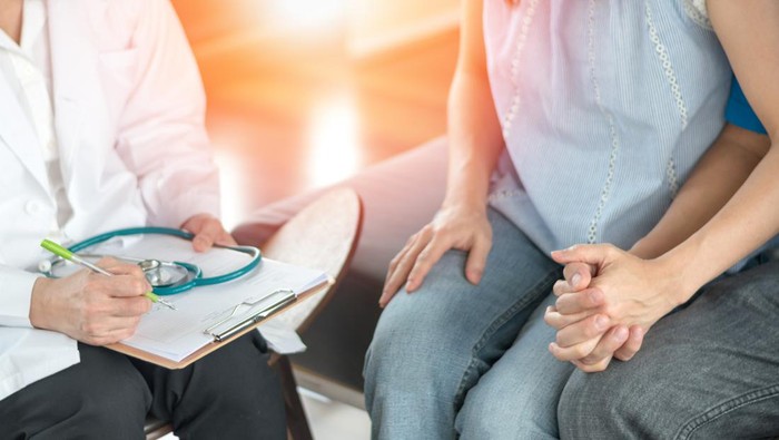 Infertility problem with marriage couple concept. A fertility doctor or reproductive endocrinologist with man and women holding hand together in therapy consult session of inability to pregnant.