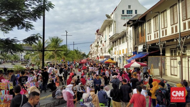 Sejumlah pengunjung berkerumun di tepi Kali Besar setelah kawasan Kota Tua, Jakarta, ditutup pada pukul 14.00, Sabtu (1/1).