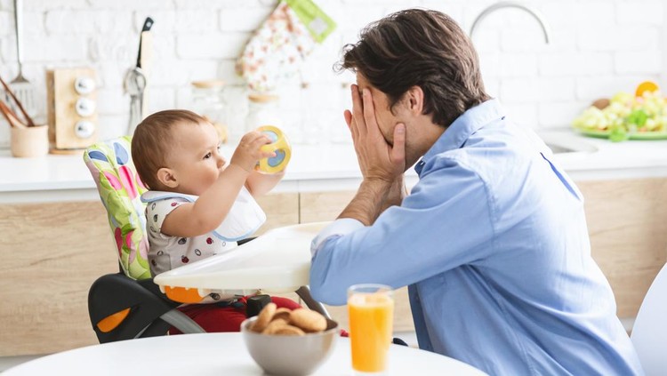 Peekaboo. Cheerful daddy playing with cute baby son in kitchen interior, empty space