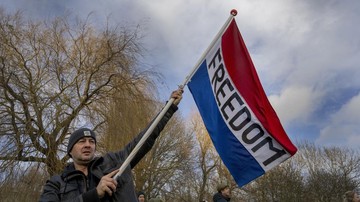 A man waves the Dutch flag as thousands of people defied a ban to gather and protest the Dutch government's coronavirus lockdown measures, in Amsterdam, Netherlands, Sunday, Jan. 2, 2022. The municipality of the Dutch capital banned the protest, saying police had indications some demonstrators could be attending 