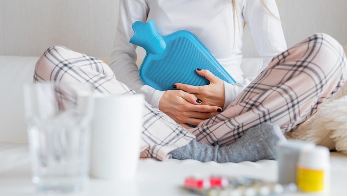 Close-up photography of unrecognisable woman with hot water bottle healing stomach pain.