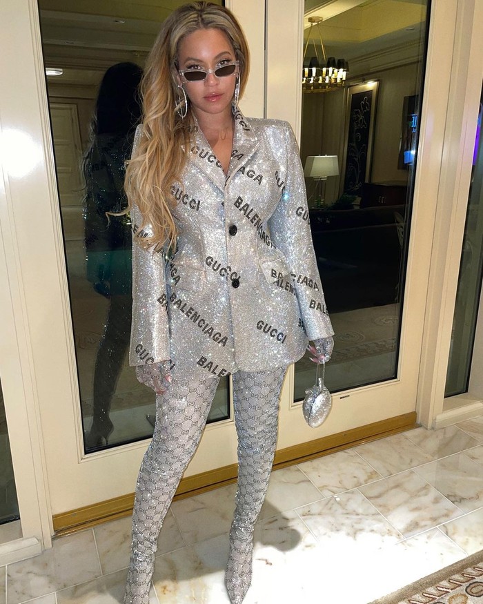 Jas berkilau berhiaskan slogan Gucci dan Balenciaga dikenakan Beyonce bersama boots senada. Di runway, busana ini hadir dalam rok selutut yang klasik. Namun Queen Bey memilih untuk tampil sexy dengannya. Foto: Instagram Beyonce