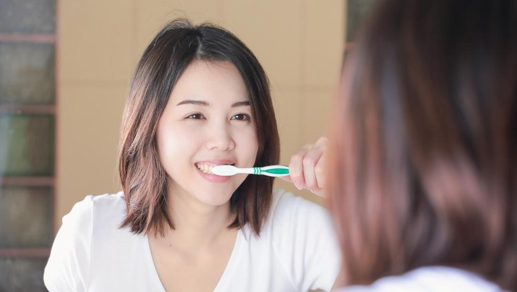 Young woman brushing her teeth at mirror. After awakening