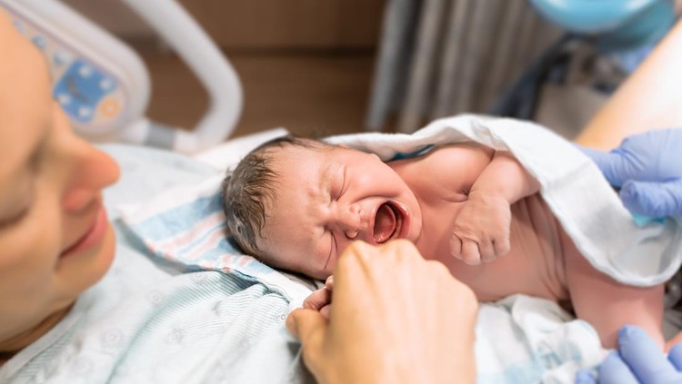 melahirkan New mom holds her newborn baby in the hospital.