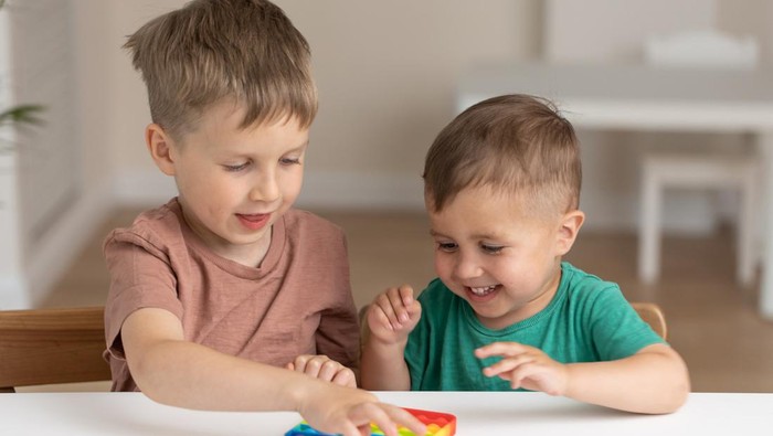 Cute children playing with the Pop It fidget. New anti stress game - push pop bubble flexible fidget. Sensory toy for discharge, development of kid
