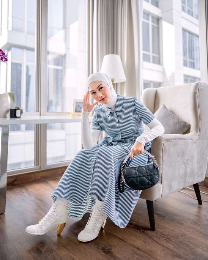 Indah Nada Puspita menunjukkan bahwa shirt dress motif garis yang kasual dapat terlihat chic ketika dikenakan bersama ankle boots dan tas bersiluet unik seperti Dior Vibe. Foto: courtesy of Dior