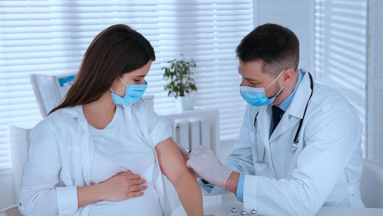 Doctor vaccinating pregnant woman against Covid-19 in clinic