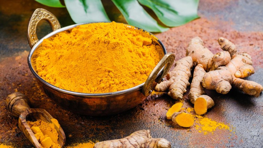 Turmeric powder and fresh turmeric on grunge dark background