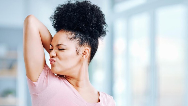 Shot of an attractive young woman smelling her armpits during her morning routine