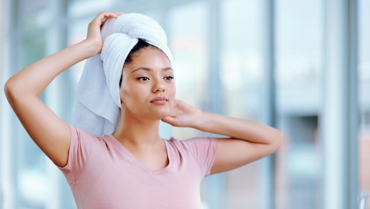 Shot of a young woman drying her hair with a towel