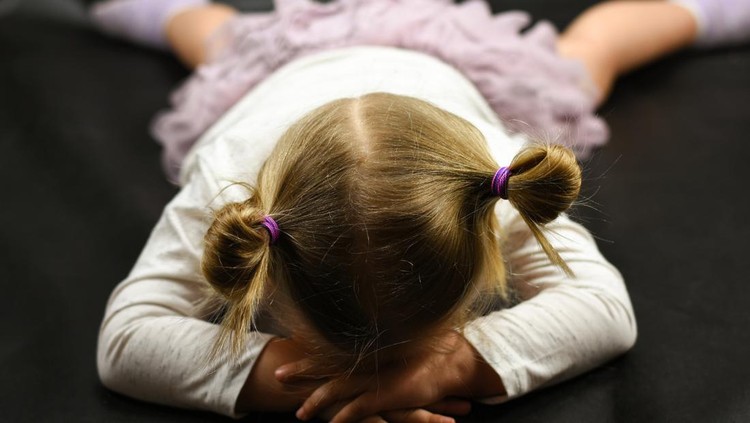 Child girl upset lying on the floor and crying on a black background