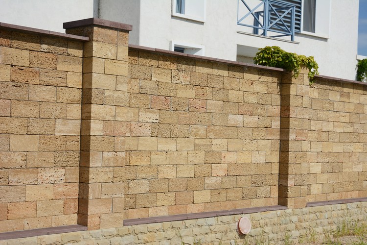 jenis batu alam untuk dinding pagar rumah A close-up on a brown oyster shell foamed brick, limestone brick fence with support pillars.