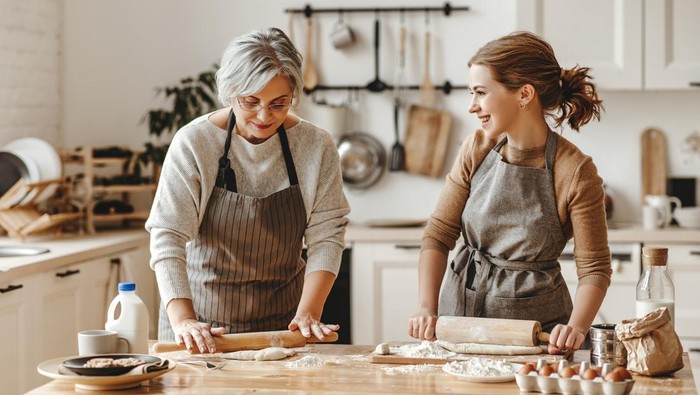 happy family grandmother  old mother mother-in-law and daughter-in-law daughter cook in kitchen, knead dough and bake cookies