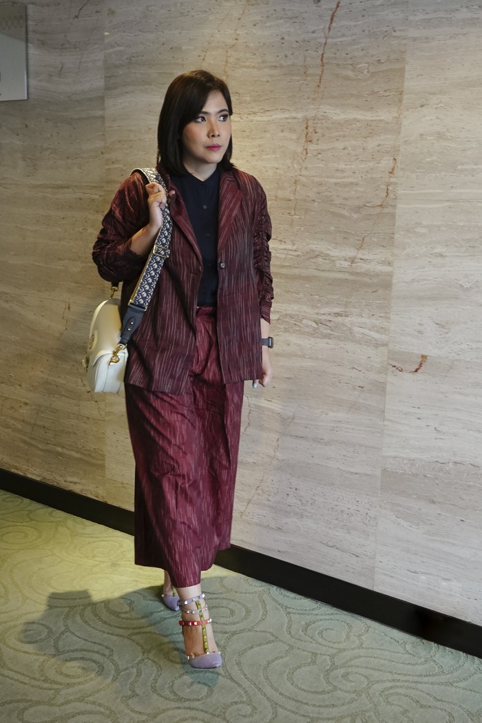 Warna merah redup dapat menjadi opsi pengganti warna hitam dan abu untuk tampil formal ke kantor. Padukan jaket dan celana kulot bersama ankle strap multiwarna untuk memberi kesan playful dan feminin. (Jaket dan celana, Nona, courtesy of Hypefast )Foto: Beautynesia