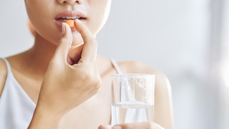 ilustrasi minum obat Woman taking tablet with glass of fresh water