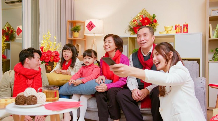 chinese new year concept - asian family watch tv together in living room happily