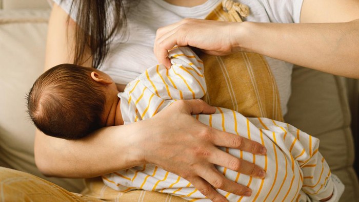 Newborn baby boy sucking milk from mothers breast. Portrait of mom and breastfeeding baby. Concept of healthy and natural baby breastfeeding nutrition.
