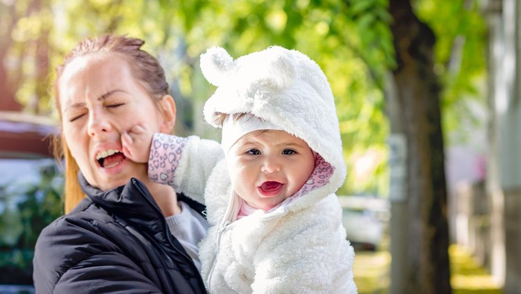 child punch and scratch her mother while laughing at the camera