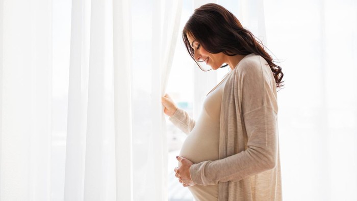 pregnancy, motherhood, people and expectation concept - close up of happy pregnant woman with big belly at window