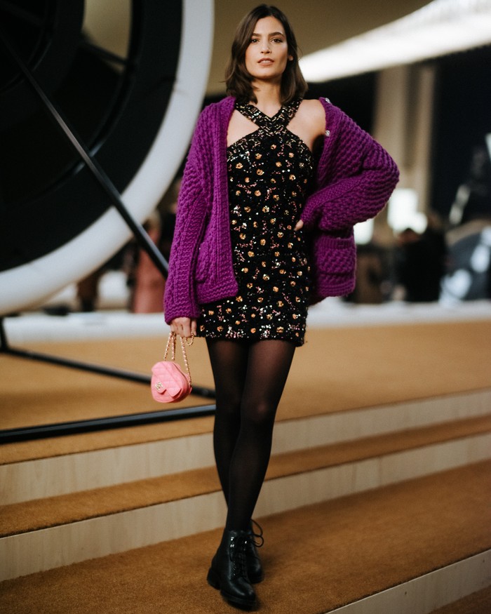 Aktris Prancis Alma Jodorowsky memilih padanan halter dress berhiaskan embroidery bersama jaket wol ungu untuk tampil glamor dan elegan. Foto: Courtesy of Chanel