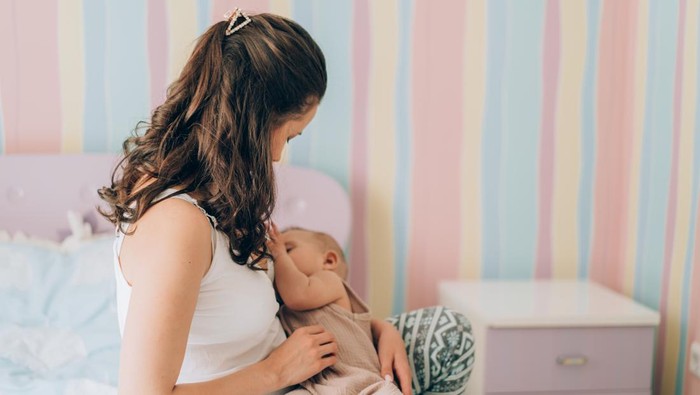 Young mother is breastfeeding her baby. In Vitro Fertilization (IVF). Family of asians.