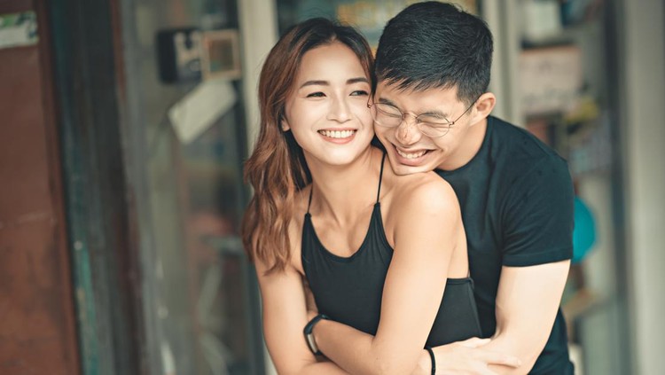 Happy Asian couple having fun and laughing together in living room at home