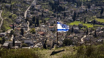 The Palestinian village of Burqa is seen as an Israeli flag is placed in the Jewish West Bank outpost of Homesh, Monday, Jan. 17, 2022. Palestinian residents of Burqa say the settlers' continued presence in Homesh, which was officially dismantled in 2005, makes it difficult to access their land and move safely in and out of their village. (AP Photo/Ariel Schalit)