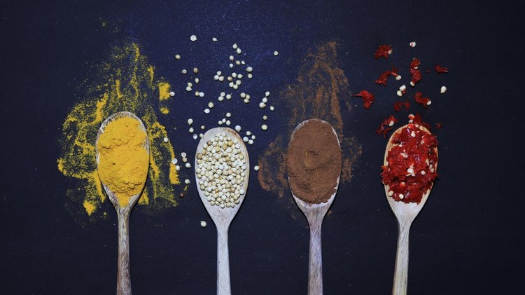 Top view of a black background with some kind of Indonesian spices for cooking placed around the border of horizontal frame useful food background. Spices included on the composition are turmeric powder, coriander, cinnamon powder, and chili.