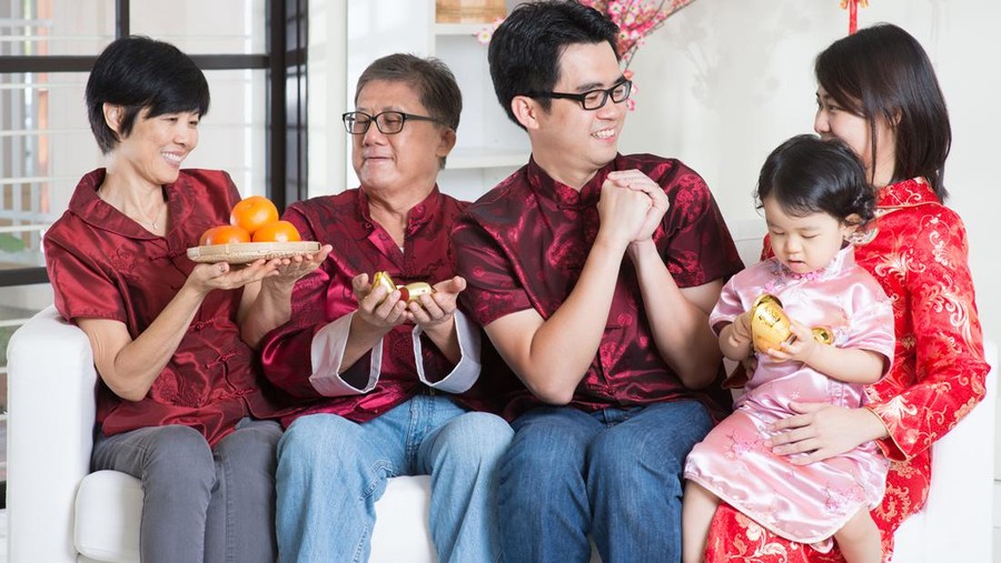 Celebrating Chinese new year. Happy Asian multi generations family in red cheongsam reunion and greeting at home.