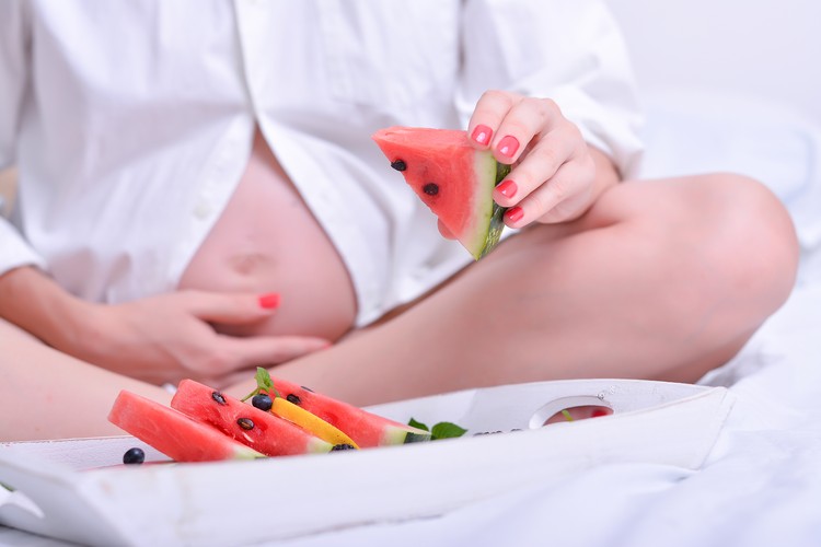 Pregnancy and nutrition - pregnant woman with a bowl of fruit and vegetables .